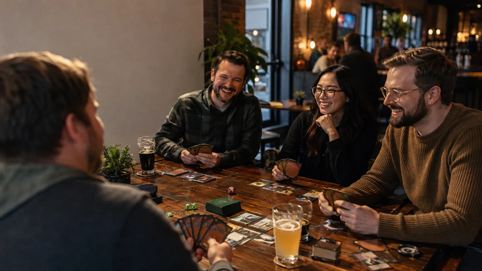 Four adults laughing together over a game of Magic: The Gathering at a cozy table